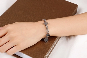 Detailed view of silver pineapple charm bracelet on wrist with tropical fruit pendants