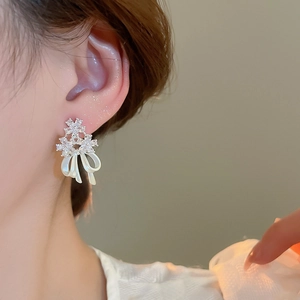 Macro detail of a 14k gold plated flower stud earring with zircon and a pearl bow charm