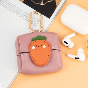 Pink faux leather earbud pouch with carrot design and gold hook on a magazine