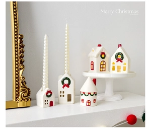 Detail of white ceramic Christmas house candle holders with candles on a white fireplace