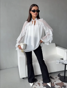Close-up of white chiffon blouse with layered ruffle sleeves and neck tie detailing