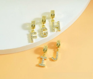 Macro view of gold zircon-encrusted alphabet pendants F to J for DIY jewelry making