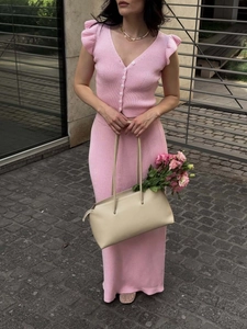 Outdoor shot of pink knitted two-piece set with V-neck top and slim-fit maxi skirt