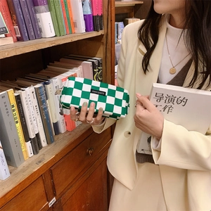 Detalle de estuche de lona de cuadros verdes con etiqueta merciparis y cremallera doble