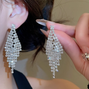 Detailed view of silver V-shape fringe earrings with shimmering diamond tassels on a model