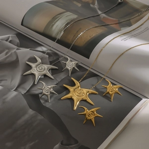 Close-up of irregular star-shaped stainless steel necklace and earrings on a magazine