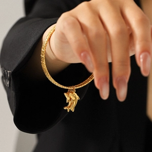 Nahaufnahme eines 18k Gold-Delfin-Armbands mit strukturiertem Armreif am Handgelenk