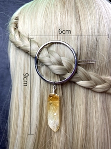 Detail of silver circular hair clip with yellow crystal drop on blonde braided hair