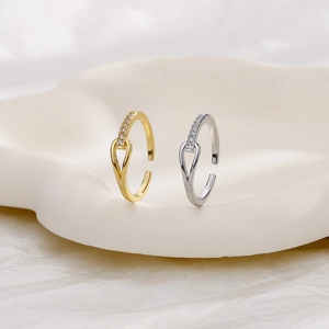 Close-up of gold and silver knot rings with cubic zirconia on a cream jewelry tray