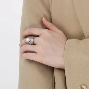 Dettaglio anello a fascia larga in argento testurizzato con perla su sfondo beige