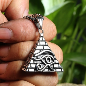 Macro detail of silver pyramid pendant with Eye of Horus carving on a steel chain