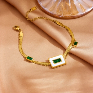 Detailed shot of a gold double-layer bracelet with green gems on champagne satin