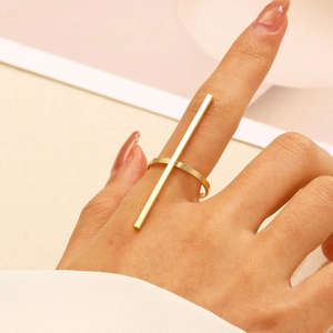 Dettaglio macro di un anello a barra verticale dorato minimalista sulla mano della modella
