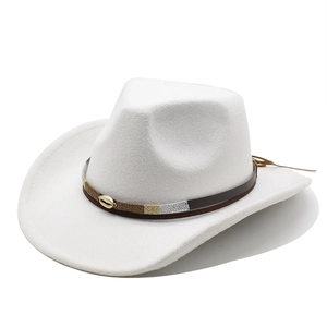 Detail of white cowboy hat featuring brown leather band and golden seashell metal accent