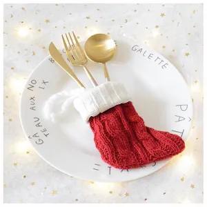 Close-up of knit Christmas sock cutlery holder with golden utensils on a plate