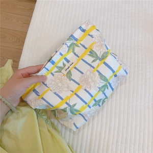 Close-up of floral cotton cosmetic bag with blue yellow plaid and brand label detail