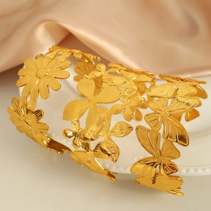 Three gold titanium steel bracelets with cut-out butterfly and daisy designs on satin