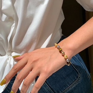 Détail du bracelet en perles d'œil de tigre et métal sur poignet au style vintage