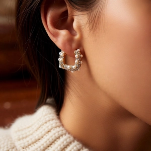 Gros plan de boucles d'oreilles en U plaqué or 18k avec perles et cristaux sur un mannequin