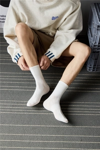 Close-up of white ribbed crew socks worn by a model in a natural lifestyle setting