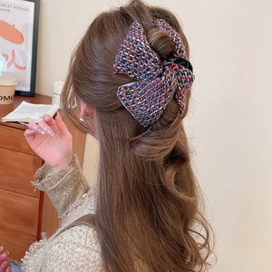 Détail de la pince à cheveux noeud en tweed montrant la texture tissée et le motif