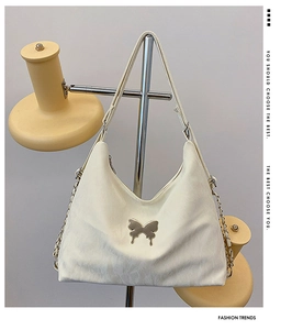 Close-up of cream underarm bag featuring cloud texture and butterfly metal buckle