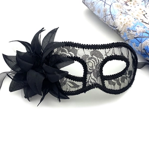 Détail d'un masque de bal masqué en dentelle noire avec fleur latérale et rubans de satin