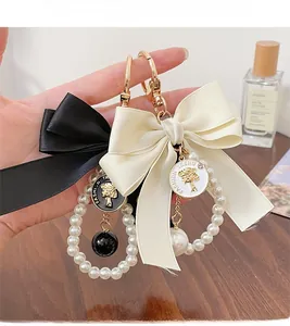 Close-up of elegant bow keychain with faux pearls and golden fashion trend pendant