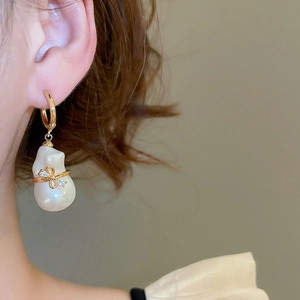 Détail de boucles d'oreilles perles baroques avec nœud doré 18k et cristaux