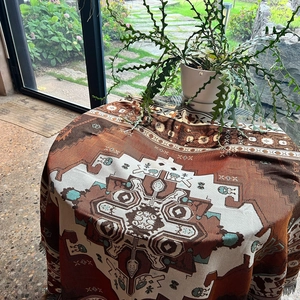 Detail of bohemian woven blanket with geometric patterns and fringe on a table