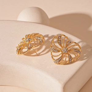 Close-up of golden hollow heart windmill earrings with white zircons on a display