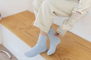 Close-up of soft blue coral fleece winter socks worn on a warm wooden staircase