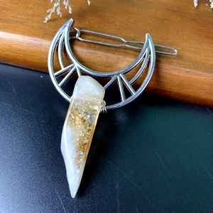 Detailed view of crescent moon hair clip with crystal pendant and gold leaf flakes inside