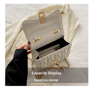 Interior view showing capacity and gold lock of this white quilted chain crossbody bag