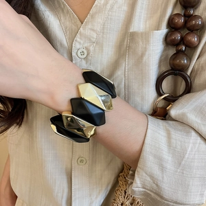 Detailed close-up of geometric black and gold stretch bracelet with irregular matte facets