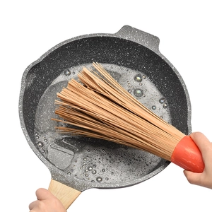 Commercial bamboo wok brush with long handle cleaning a stone non-stick frying pan