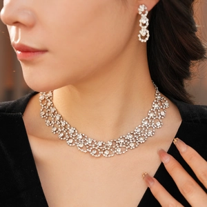 Close-up of model wearing silver hollow floral necklace and tassel earrings with rhinestones