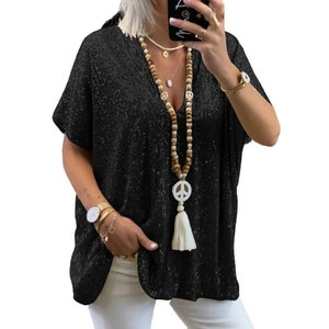 Dettaglio ravvicinato della maglietta nera con scollo a V e paillettes con gioielli boho