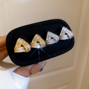 Close-up of geometric triangle stud earrings with pavé zirconia in gold and silver