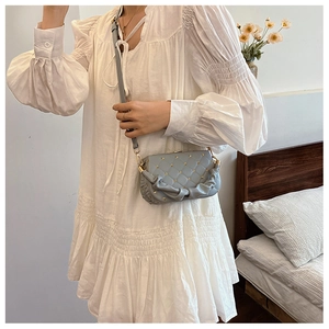 Detailed view of light blue quilted crossbody bag with stylish pleated edges on model