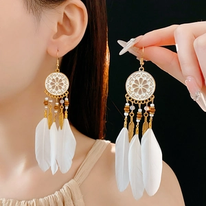 Détail de boucles d'oreilles attrape-rêves bohèmes avec émail blanc et plumes