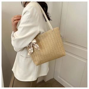 Sac fourre-tout en paille kaki avec foulard en soie décoratif porté par un mannequin