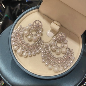 Macro detail of silver pearl earrings with zircon inlay on a teal jewelry gift box