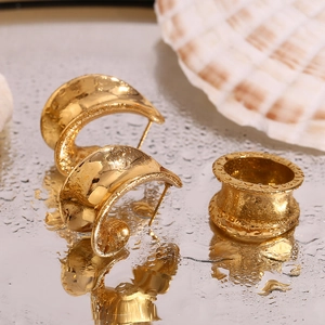 Vue macro d'un ensemble bijoux dorés sur un miroir avec gouttes d'eau et coquillage
