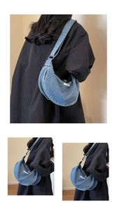Detail of blue denim crescent bag with wash finish and adjustable shoulder strap