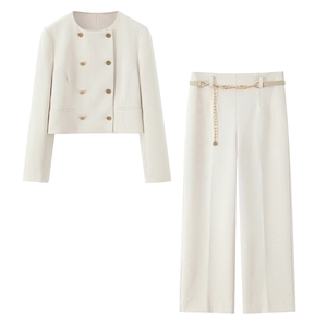 Dettaglio del blazer corto crema con bottoni dorati e pantaloni con cintura a catena