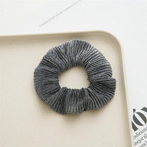 Detail shot of black and white pleated polyester hair scrunchie on a white tray