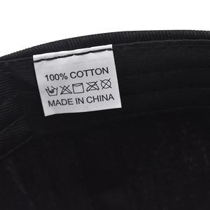 Gros plan de l'étiquette de lavage d'une casquette en coton noir indiquant 100% pur coton