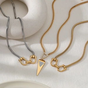 Detail of layered gold and silver chains with geometric cone and horseshoe pendants