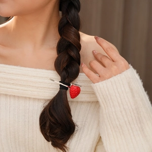 Dettaglio di un fermaglio per capelli a forma di fragola rossa su una treccia chic